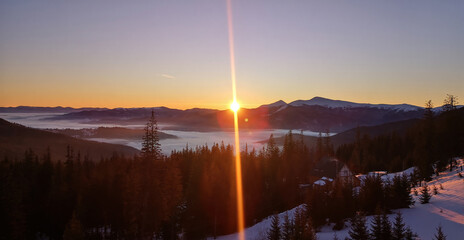 Scenic winter Carpatian mountain landscape with snowy slope panoramic view soft sunrise clouds and distant peaks in calm natural atmosphere.
