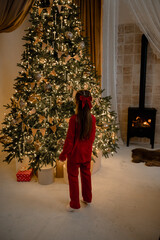 Little girl in red pajamas near the Christmas tree, New Year holiday, Christmas