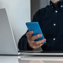 Professional simultaneously operating laptop and smartphone, highlighting multitasking and digital connectivity in modern work