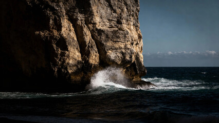Waves crashing against a rugged sea cliff at dusk