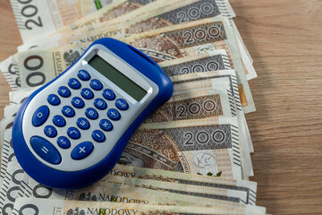 200 Polish zloty money with blue calculator on desk, finance accounting, budgeting and investment concept