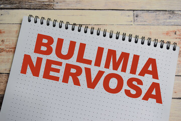 Concept of bulimia nervosa write on book isolated on Wooden Table. eating disorder characterized by binge eating followed by purging concern