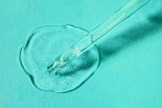 Liquid cool blue pipette gel or serum on marine blue textured paper background. Beauty product sample swatch