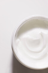 Cosmetic white colored cream in a plastic jar top view. Beauty skin care beauty product sample swatch on white background