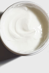 Cosmetic white colored cream in a plastic jar top view. Beauty skin care beauty product sample swatch on white background