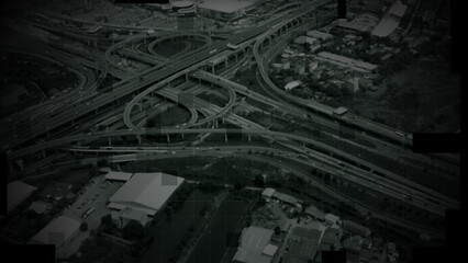 Aerial surveillance, military reconnaissance view of a complex highway interchange with HUD targeting graphics, creating a cinematic spy-drone atmosphere and intelligence-operation mood