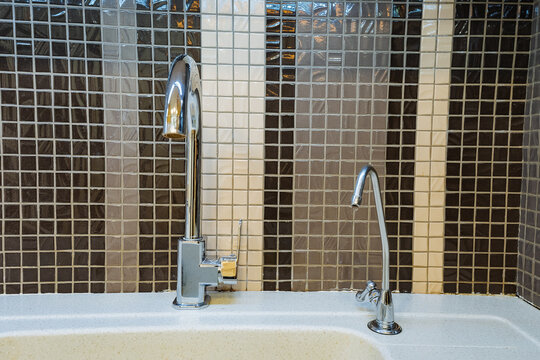 chic green tap, sleek environmentally conscious faucet with dual handles and artistic backdrop, stylish sustainable sink tap featuring water filtration and decorative mosaic design