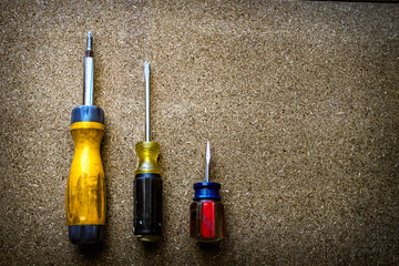 screwdrivers with different types and sizes of tips and handles isolated on a wood grain surface. home improvement background banner with copy space.