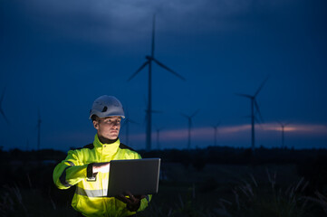 Engineers wearing safety helmets and jackets inspecting a wind turbine at a wind farm at dusk. Concept renewable energy.