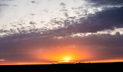 Obraz premium Witness a sunset glowing over a field with a cloudy sky