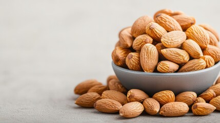 A bowl overflowing with almonds, showcasing their textured skins and natural hues against a subtle background.