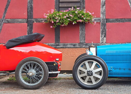 Contrasting Bugatti vintage cars parking by a half-timbered house
