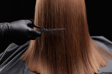 Hairdresser with scissors and female client with brown hair impeccable haircut