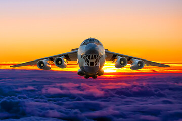 Front view of the white wide body transport cargo airplane flying above the cumulus sunset sky