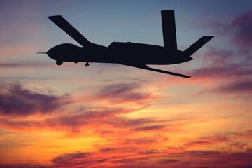 Silhouette of an American MQ-20 Avenger attack and reconnaissance drone at sunset. Illustration of a US Army MQ-20 Avenger unmanned aerial vehicle. Aerial reconnaissance using UAVs in the military.