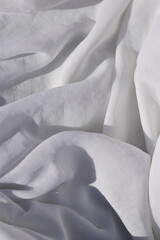 Pano de algodão amassado, tecido macio branco com curvas e linhas orgânicas visto de cima