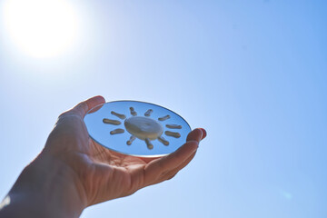 Hand holding mirror reflecting sunscreen sun protection