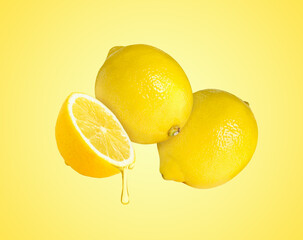 Drop of juice dripping from citrus fruit. Fresh lemons on yellow background