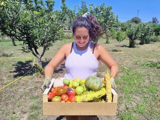 Woman Carrying a Box of Fresh Organic Vegetables in a Sunny Orchard
