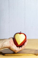 Hand showing an apple with a carved heart