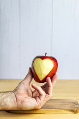 Hand showing an apple with a carved heart