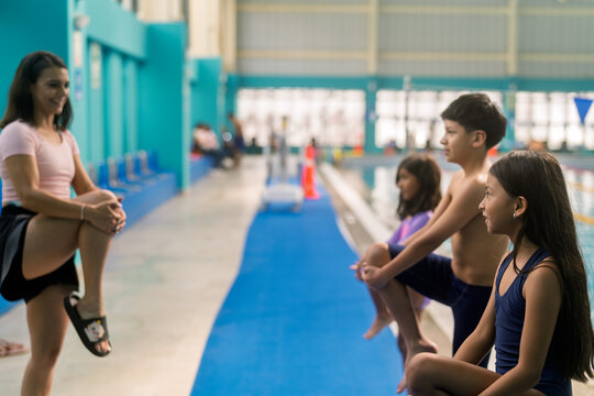 Children warming up for swimming lessons with instructor