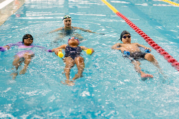 Children learning to swim during lesson with instructor