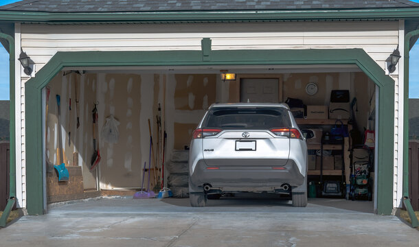 Calgary, Alberta, Canada. Nov 18, 2025. Toyota RAV4 parked in open residential garage with visible storage items in Calgary, Alberta, Canada.