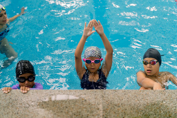 Children practicing swimming skills during a pool lesson