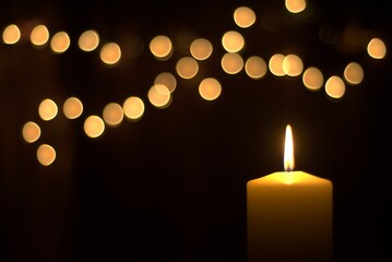 candle and Christmas lights on black background