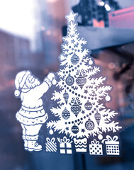 A Santa Claus with a Christmas tree, used as a festive decoration on a glass window or display case. Decoration for Christmas and New Year. Close-up. Selective focus.