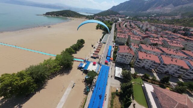 An exhilarating footage of a parachutist gliding gracefully under the bright midday sun, capturing the thrill of adventure and the beauty of the surrounding landscape,oe01