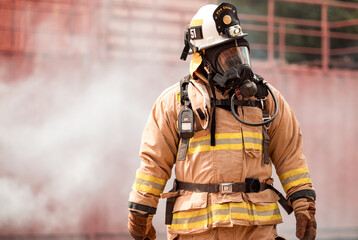 Naklejka premium A firefighter in full protective gear takes a break after exiting a smoke-filled building