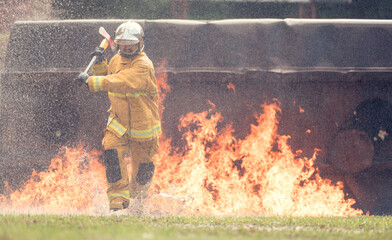 A firefighter in full protective gear runs through intense flames while holding a rescue axe