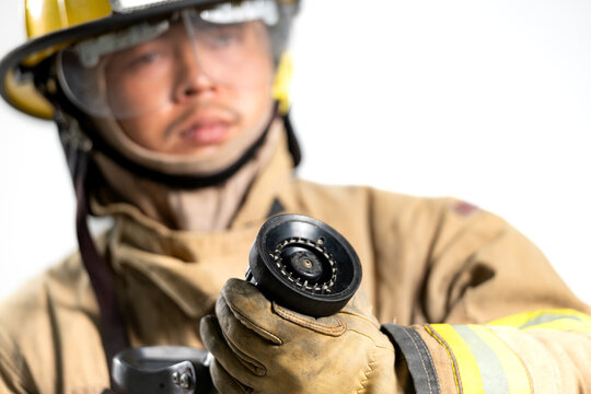 Portrait of a firefighter in protective uniform holding a firefighting and fire hose nozzle - Powered by Adobe