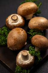 Fresh cremini mushrooms and parsley on dark board