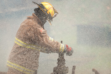 A firefighter in protective gear manually turns off a water valve