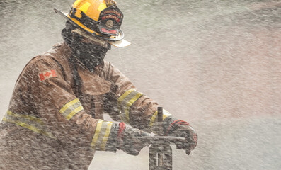 A firefighter in protective gear manually turns off a water valve