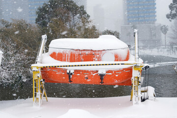Enclosed lifeboat covered in snow mounted on a launching system near a lake