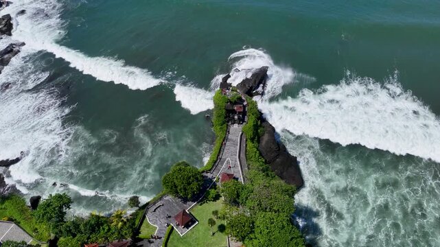 Drone video of an aerial view of Tanah Lot beach with rocks jutting out into the beach
