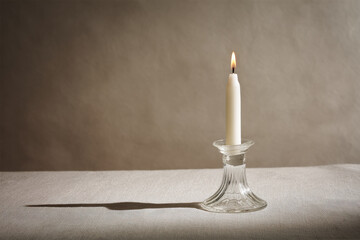 slender candle delicately perched in fragile glass holder casting soft shadows with rustic linen tablecloth serving