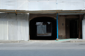 the facade of a building with an arch, covered with scaffolding