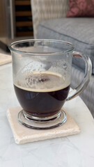 Glass mug on coaster with black coffee on modern table for coffee shops, interior designers, concept of cozy cafes