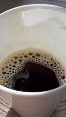 Close-up of freshly brewed black coffee in white cup with sunlight and textured surface concept of cafés, coffee shops, beverage brands