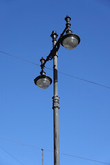Retro vintage style street pole with two lamps over clear blue sky close-up view