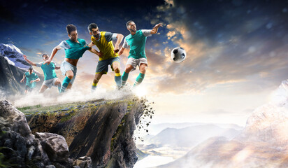 Soccer players in action high in the mountains on the edge of a cliff. Sports concept. Extreme sports moment. Panorama. Cliff. Football players.
