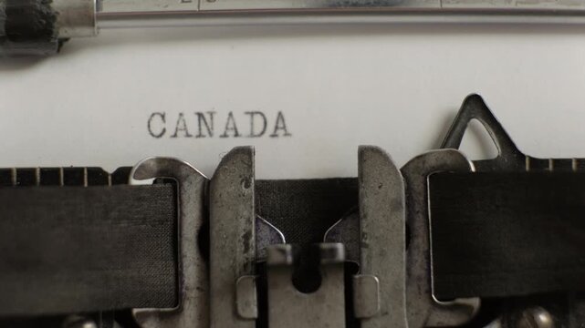 Canada word being typed on old vintage typewriter on white sheet of paper close-up