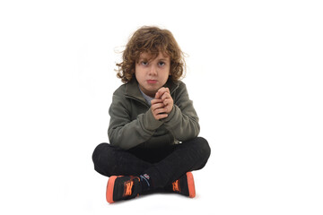 front view of  boy dressed in sportswear sitting on the floor looking at camera on a white background