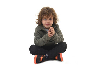 front view of  boy dressed in sportswear sitting on the floor looking at camera and smiling on a white background
