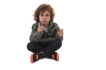 front view of  boy dressed in sportswear sitting on the floor looking at camera showing the number one with your finger  white background